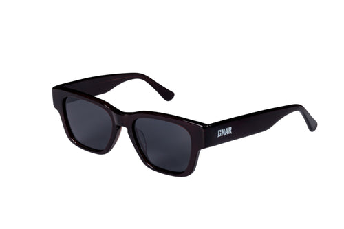 Front three quarter view of Gnar optics Disaster sunglasses with dark acetate burgundy rectangular frames, dark polarized lenses and a white GNAR logo on arms.