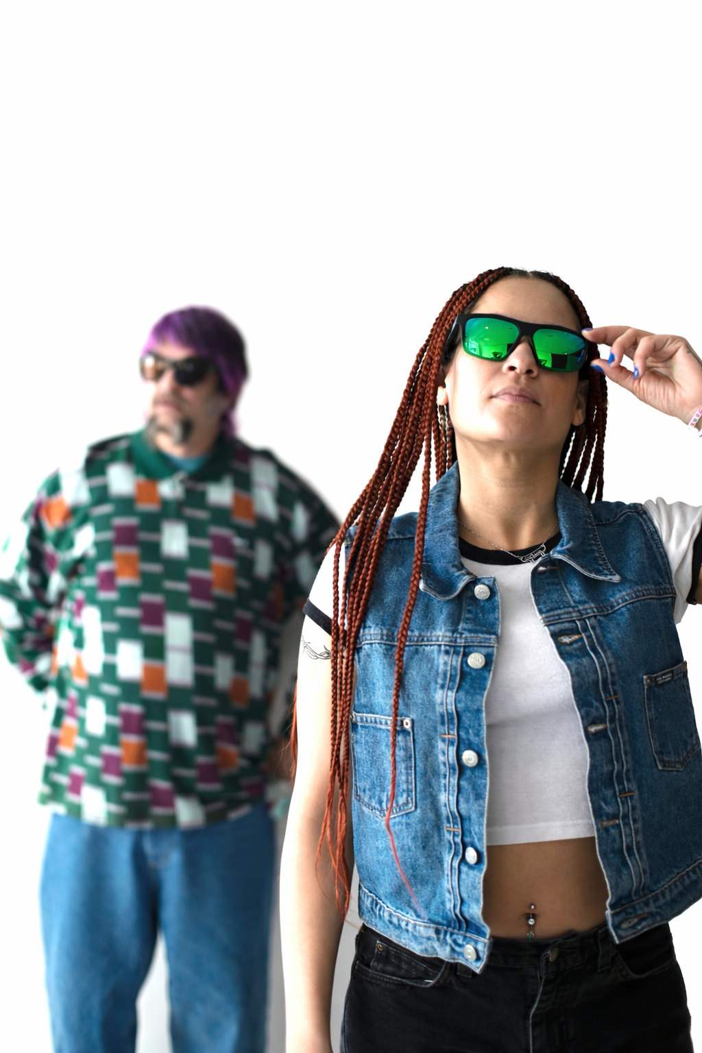 Woman with long red and black braids wearing Gnar Optics Krook sunglasses with green mirrored polarized lenses while a second person stands in the background