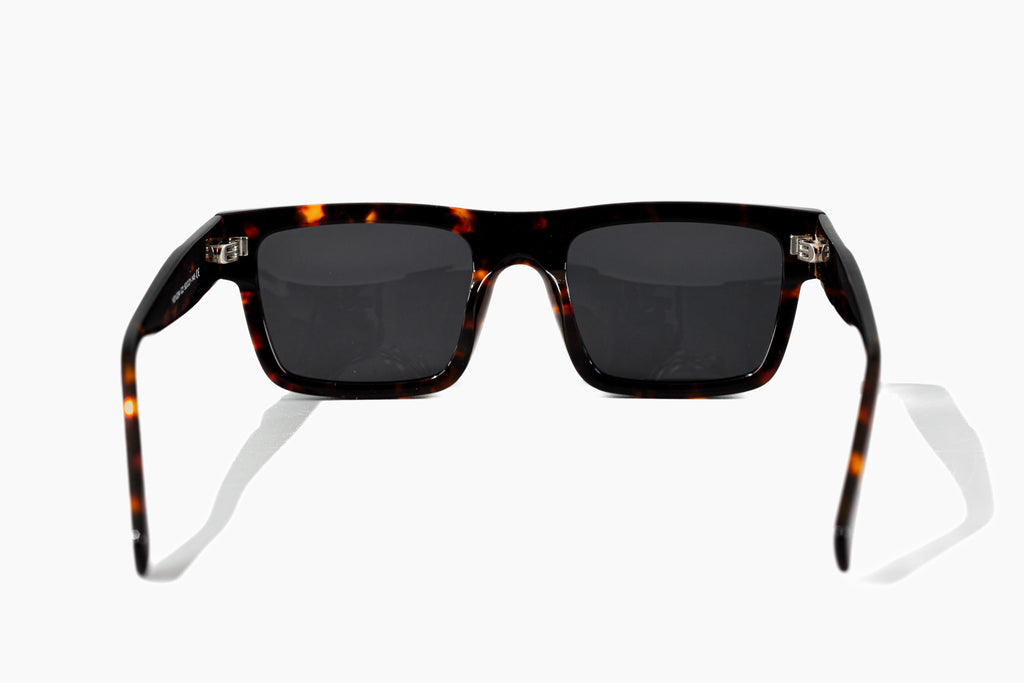 Sunglasses with tortoiseshell frame and dark lenses on a white background