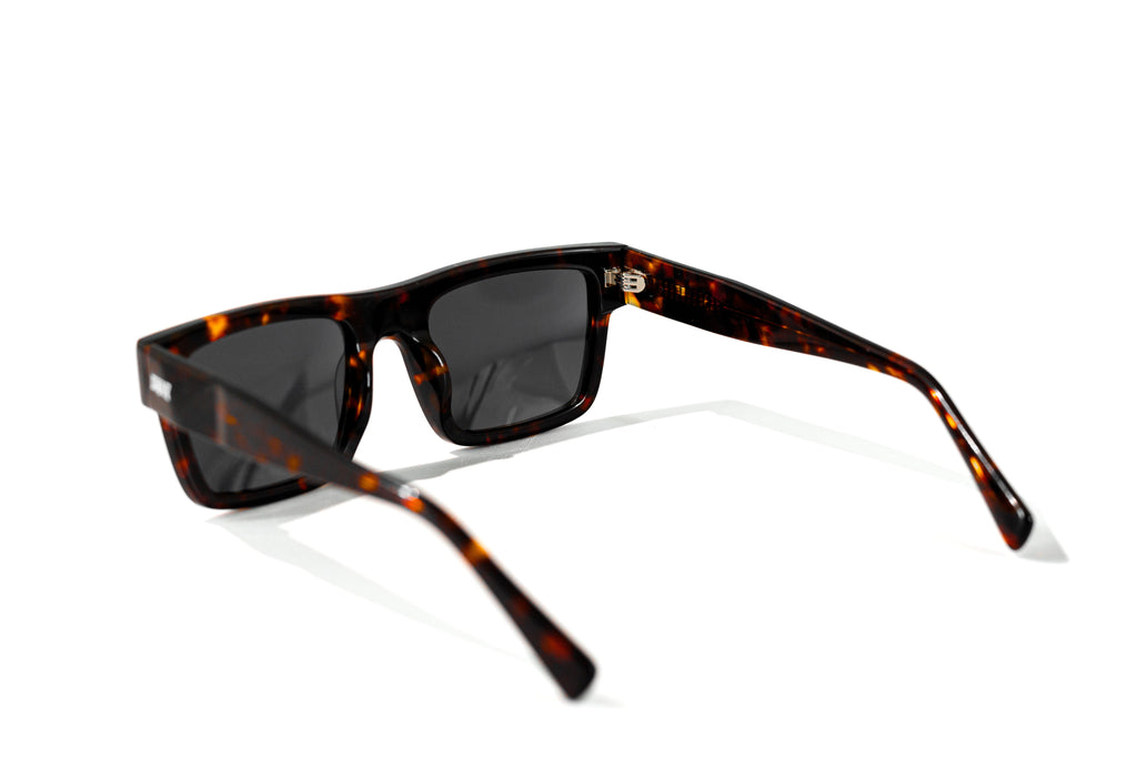 Sunglasses with tortoiseshell frame and dark lenses on a white background